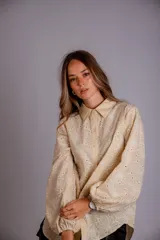 Camisa de manga larga con diseño abullonado, confeccionada en tela bordada con motivos florales. Presenta cierre frontal con botones y puños elásticos.