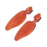 Par de aros colgantes color naranja con glitter, con forma de paleta alargada y botón superior.