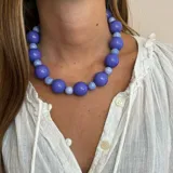 Collar corto de cuentas grandes color rojo brillante. Las cuentas son esféricas y de diferentes tamaños.