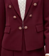 Blazer de sastrería entallado de color bordó, con solapas de muesca, cierre cruzado de botones dorados y bolsillos con solapa en los laterales.