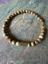 Collar de piedras naturales en tonos tierra, con detalle de tubo dorado en un lateral y cierre marinero dorado.