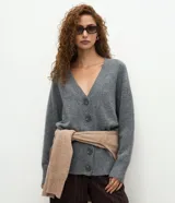 Cardigan de punto gris con escote en V, cierre frontal con botones grandes y mangas largas. Presenta un diseño de corte recto y estructura clásica.