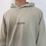 Canguro oversize color beige con capucha y estampado gráfico en la espalda que incluye un esqueleto de pez y texto descriptivo.