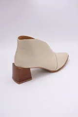 Botines de cuero color beige con diseño de tajo frontal, punta fina y taco cuadrado de madera.