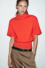 Top de punto liso color rojo, con cuello subido, manga corta con hombreras y bajo acabado en rib.
