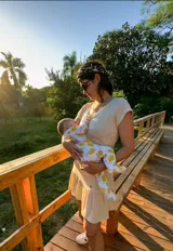 Vestido de algodón elastizado color beige claro, con escote en V y mangas cortas. Presenta una falda con volados y apertura sutil para lactancia.