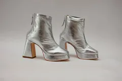 Botinetas plateadas de cuero con plataforma y taco cuadrado. Cierre con cremallera en la parte posterior.