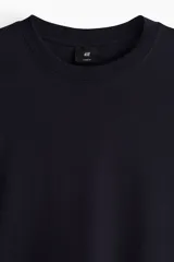 Remera de manga larga color azul marino, de punto de algodón de peso medio, con cuello redondo acanalado, hombros caídos, puños acanalados y bajo recto. Presenta un corte holgado.