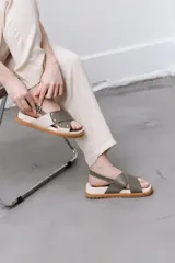 Sandalias bajas color verde oliva, con dos tiras anchas cruzadas sobre el empeine y tira trasera con hebilla.