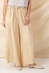 Pantalón italiano ancho color crudo, con cintura elastizada, cinto trenzado y bolsillos laterales.