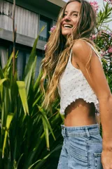 Top blanco de broderie con tirantes finos y volados en el ruedo.