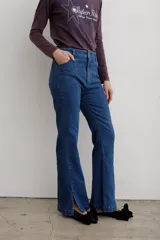 Jean de denim azul de tiro medio, con corte flare y costuras frontales destacadas.