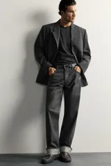 Blazer de corte regular fit color gris oscuro, confeccionado en tejido con lana. Cuenta con cuello con solapas de muesca, cierre frontal con tres botones, bolsillos con solapa en la cadera y un bolsillo de vivo en el pecho.