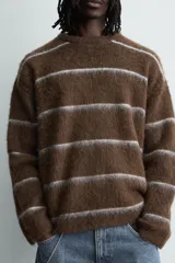 Jersey de punto con textura, corte relajado, cuello redondo y manga larga. Presenta un diseño de rayas horizontales en tonos marrones y grises con acabados en rib.