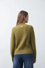 Polera de punto color marrón, con cuello alto y diseño de trenzas verticales en el frente y tejido acanalado en las mangas. Presenta mangas raglán y terminaciones acanaladas en puños y ruedo.