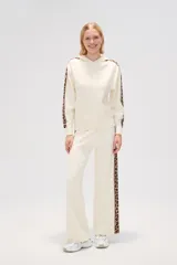 Pantalon de tejido de punto color crema, de corte ancho y tiro alto. Presenta una franja lateral con estampado animal print a lo largo de ambas piernas.