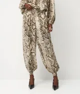 Pantalón tipo aladino confeccionado en chiffon con estampado de piel de serpiente. Presenta cintura alta con elástico y puños ajustados en los tobillos, ofreciendo una silueta holgada y fluida.