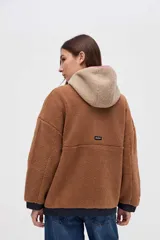 Campera de sherpa con diseño de bloques de color en tonos marrones y beige, con capucha, cierre frontal y detalles en nylon azul marino.