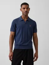 Buzo tipo polo de punto color azul, de manga corta, con cuello camisero, detalles de tejido vertical y bordado pequeño en el pecho.