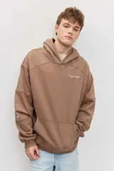 Canguro marrón con capucha, bolsillo frontal tipo kango y diseño oversize de corte relajado con mangas largas.