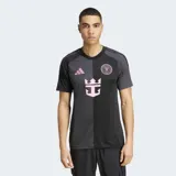 Camiseta de fútbol Adidas para hombre, modelo visitante del Inter Miami CF temporada 25/26. Diseño dividido verticalmente en dos tonos de negro/carbón, con detalles en rosa (logo Adidas, escudo del club y patrocinador principal con forma de ancla/corona).