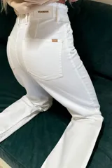 Jean de mezclilla color blanco roto (off-white) de corte recto, con detalle desflecado en el borde de la cintura y en los tobillos. Presenta costuras claras y botón metálico en el cierre.