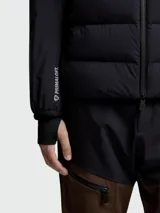 Campera puffer Moncler modelo Agaripe en color azul marino, diseñada con un cuerpo acolchado y mangas de tejido técnico. Incluye cuello alto, cierre frontal de cremallera, puños con orificios para el pulgar y aislamiento PrimaLoft.