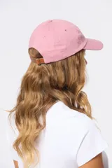 Gorro con visera de lona rosado con bordado frontal en tonos verde y violeta.