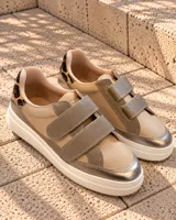 Zapatillas urbanas de cuero color beige y gris metalizado con cierre de doble velcro, detalle animal print en el talón y suela chunky blanca.