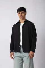 Camisa de manga larga con textura suave y calce suelto, con cierre frontal de botones y cuello clásico.