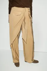 Pantalón de tiro bajo con diseño cruzado tipo pareo en el frente y lazo ajustable. Presenta pernera recta y cierre lateral con cremallera oculta.