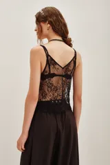 Top de encaje color beige con diseño floral, escote en V y breteles finos. Presenta detalles de bordado con pequeñas cuentas brillantes y terminación con festones en el ruedo.