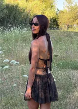 Vestido corto color chocolate con cuello halter y escote drapeado. Presenta un diseño con falda fluida y short incorporado, confeccionado en tela liviana y traslúcida.