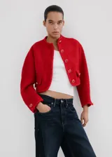 Chaqueta corta roja de tejido texturizado, con cuello redondo, cierre frontal de botones y bolsillos con solapa en el frente.