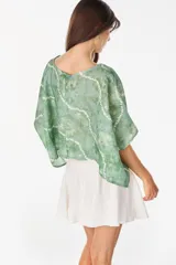Blusa de lino italiano color blanco, con diseño holgado, escote asimétrico estilo off-shoulder y mangas cortas amplias.