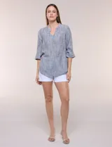 Blusa de silueta relajada con textura tramada, color azul con rayas verticales en tonos rosados, celestes y amarillos. Cuenta con cuello mao abierto en V y mangas tres cuartos amplias con pequeña abertura lateral en el puño.