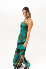 Vestido largo con estampado abstracto en tonos verdes, azules y negros. Presenta tirantes finos y cuello halter cruzado con detalle de abertura en el pecho.