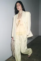 Top sin mangas color crudo, con escote en V y cierre frontal con lazos. Presenta bordados florales y detalles de encaje.