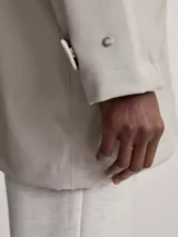 Piloto de lluvia color beige con capucha y cierre frontal.