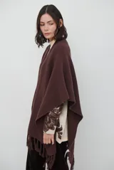 Ruana de tejido de punto en color negro, con diseño de cuello alto y terminaciones con flecos en los bordes.