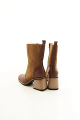 Bota de caña media combinada en cuero liso y descarne color marrón, con punta cuadrada, cierre lateral y taco ancho de madera.