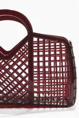 Bolso shopper de red color bordó, elaborado en plástico con diseño geométrico calado y doble asa superior rígida.