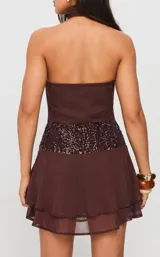 Vestido corto color marrón, con cuello halter, falda con volados y una faja central decorada con lentejuelas brillantes.