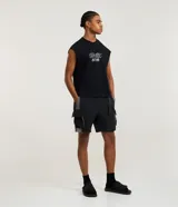 Bermuda baggy de poliéster para hombre, color negro con recortes contrastantes en gris y bolsillos cargo laterales. Cuenta con cintura elástica y cinturón ajustable.