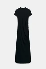 Vestido largo negro de cuello redondo y manga corta, con detalle de drapeado lateral, bajo con abertura lateral y cierre de cremallera en la espalda.