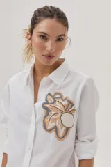 Camisa blanca de algodón y lino con bordado de flor en el frente.