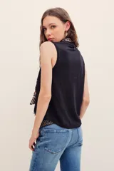Musculosa negra de encaje con cuello redondo y diseño sin mangas, de corte holgado.