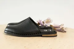 Mules de cuero negro con tachas plateadas en el borde de la suela y plantilla con logo estampado.