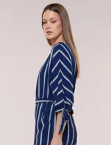 Enterito largo de crepe color azul marino con diseño de rayas verticales blancas. Cuenta con escote redondo, mangas tres cuartos con detalles de lazos en los puños, cintura elastizada con lazo extraíble para ajustar, bolsillos laterales y pantalón de corte amplio.