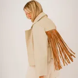 Campera de cuero beige con solapas amplias y flecos largos de cuero marrón en la espalda.
